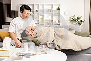 Caring Man Comforts Sick Woman Resting on Couch at Home