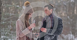 A caring man warms his wife`s hands in the winter on the street in a snow-covered Park