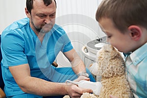 Caring medical worker examining the boy and his teddy bear