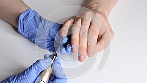 Caring for men`s nails. Manicurist in the salon in blue gloves makes a manicure for a man. Men`s beauty concept