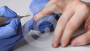 Caring for men`s nails. Manicurist in the salon in blue gloves makes a manicure for a man. Men`s beauty concept