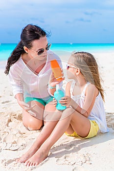 Caring mom applying sun cream to kid nose on white beach. The concept of protection from ultraviolet radiation