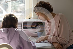 Caring mom help teen daughter with homework assignment photo