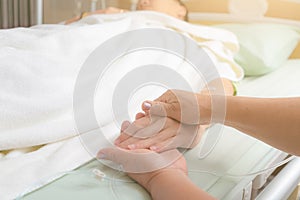Caring mom holding kind of son hands in bed
