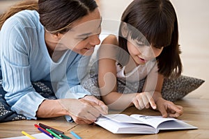 Caring mom reading interesting book with small daughter