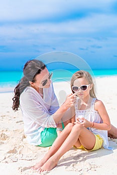 Caring mother applying sun cream to daughter nose on the beach. The concept of protection from ultraviolet radiation