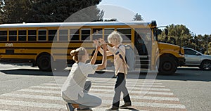 Caring mother escorting son to school bus. Mom watch child boarding schoolbus.