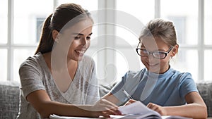 Caring mother help daughter with school assignment at home