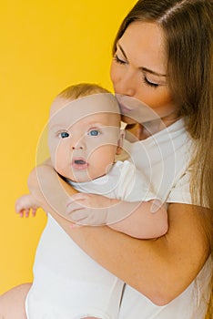 Caring mother holds her baby son in her arms and kisses him