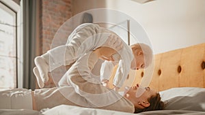 Caring Mother Lying on a Bed, Playing with a Cute Newborn Baby at Home. Mom Bonding with a Toddler