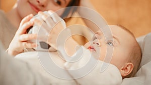 Caring Mother Lying with a Cute Newborn Baby in Bedroom. Mom Bonding with a Toddler, Kissing Infant