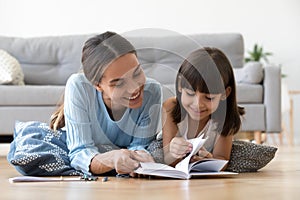 Caring mother reading book with little kid girl at home