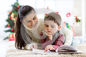 Caring mother reads to her child an interesting book on Christmas Eve