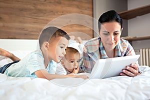 Caring mother showing tablet to her children