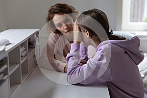 Caring mother talking to stressed adolescent daughter.