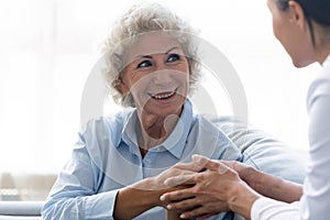 Caring nurse holding older woman hands, expressing support and empathy