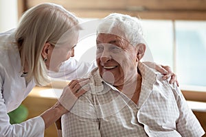 Caring nurse talking to elderly patient 80s man