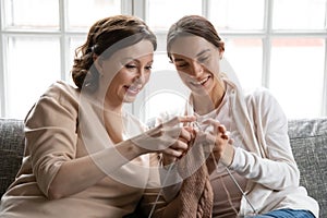 Caring old mom teach adult daughter knitting