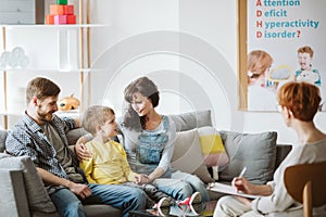 Caring parents and misbehaving boy during therapy session with counselor