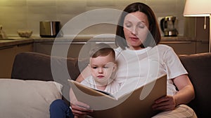 Caring pregnant mother nanny carefully reads her son boy book with fairy tale. Mother teaches child to read book