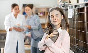 Caring preteen girl standing in animal shelter with kitten in arms