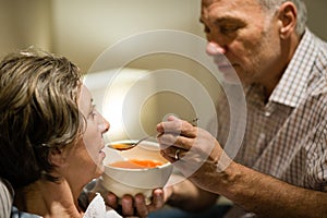 Caring senior man feeding his sick wife