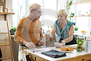Caring wife giving a breakfast to her attractive aging spouse