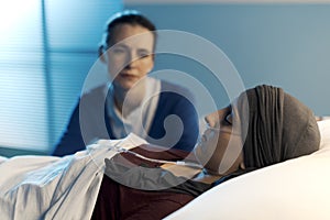 Caring woman assisting her friend with cancer at hospital