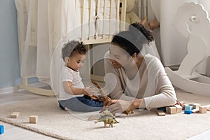 Caring young happy african ethnicity mother playing toys with kid.