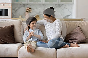 Caring young indian mother talking with small kid son.