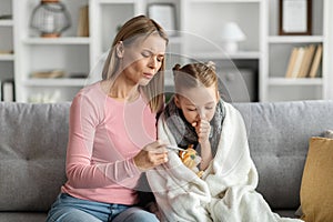 Caring Young Mom Checking Temperature Of Her Sick Child At Home