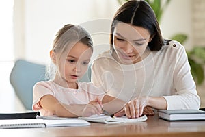 Caring young mom studying with small daughter