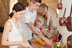 Caring young parents cook together with their son in the kitchen