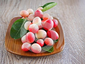 Carissa carandas or karonda are white and red with green leaves in wooden plates. On the old wood table It is a small fruit