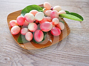 Carissa carandas or karonda are white and red with green leaves in wooden plates. On the old wood table It is a small fruit