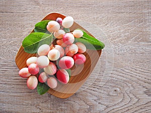 Carissa carandas or karonda are white and red with green leaves in wooden plates. On the old wood table It is a small fruit