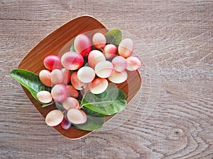 Carissa carandas or karonda are white and red with green leaves in wooden plates. On the old wood table It is a small fruit