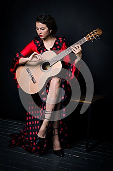 Carmen beautiful woman in red dress, with guitar on dark background
