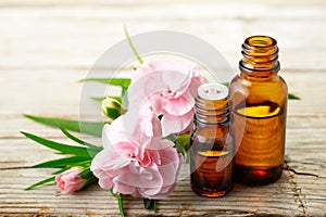 Carnation absolute essential oil and pink flowers on the wooden table