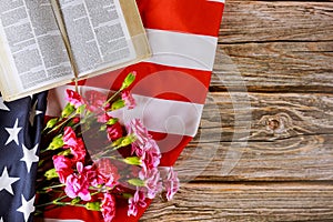 Carnation flowers on Open reading Bible on a close up in the American flag