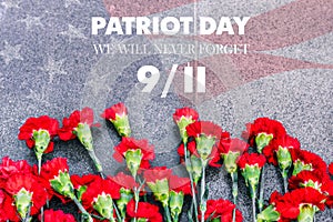 Carnations on the memorial with the American flag and the phrase patriots Day. September 11. We will never forget. Anniversary