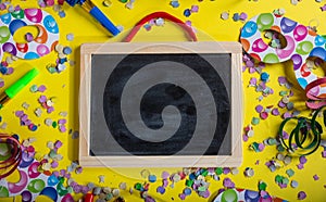 Carnival or birthday party. Blank blackboard, confetti and serpentines on bright yellow background