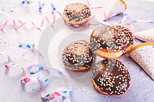 Carnival food. German Krapfen or donuts with streamers and confetti. Traditional Berliner for carnival and party