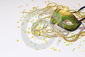 Carnival green and gold masks and beads on a white background.