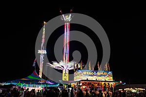 A carnival with a lot of people and a tall ride