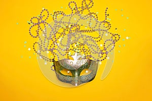 Carnival mask and beads on a yellow background.