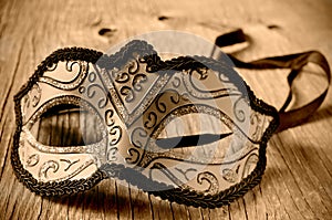 Carnival mask on a wooden surface in sepia toning