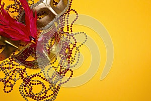 Carnival masks and beads with copy space on yellow background.