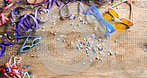Carnival party. Glasses, confetti and serpentines on wooden background, top niew