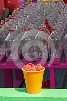 Carnival ring toss game with a yellow cup full of red rings in the foreground